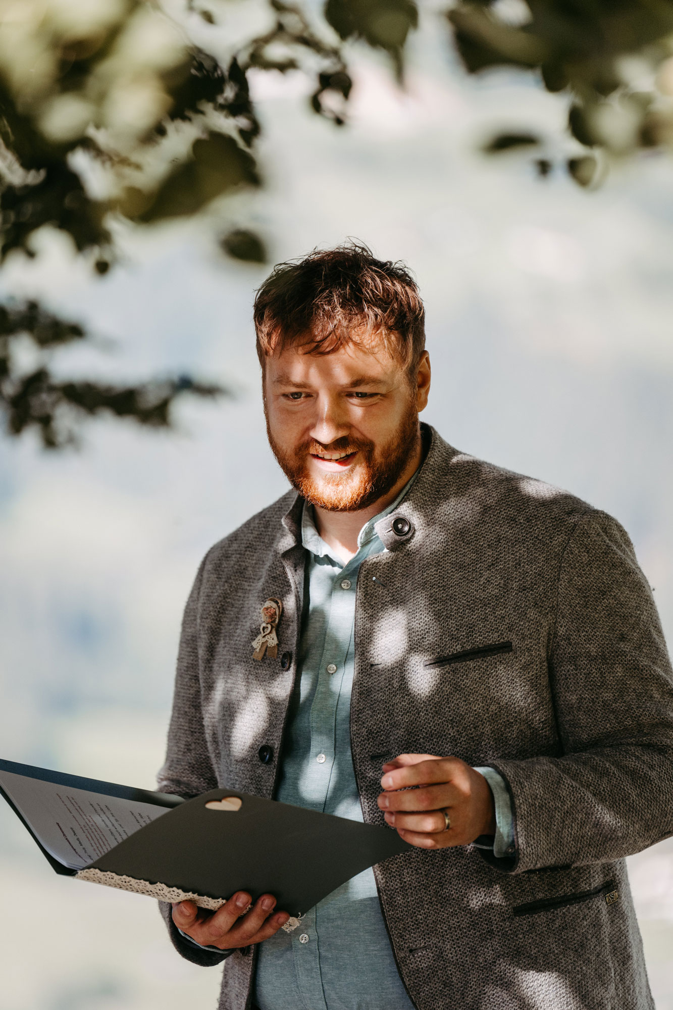 Freier Trauredner hält eine persönliche Rede im Freien, lächelnd und in traditioneller Jacke – authentische und emotionale Hochzeitszeremonie.